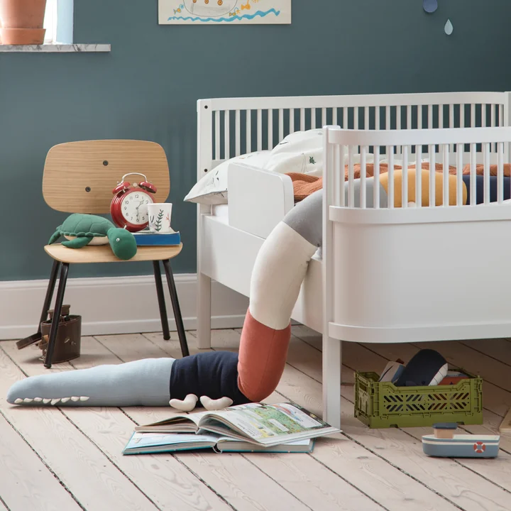 The Sleepy Croc pillow and the Oakee chair from Sebra next to the white crib