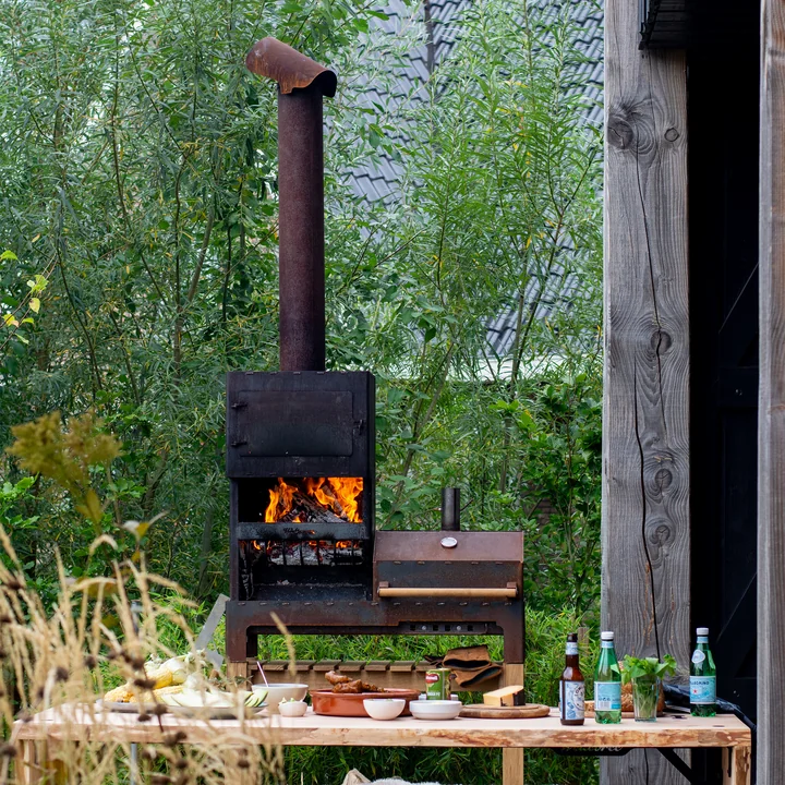 The Outdoor steel stove XL from Weltevree behind an outdoor dining table