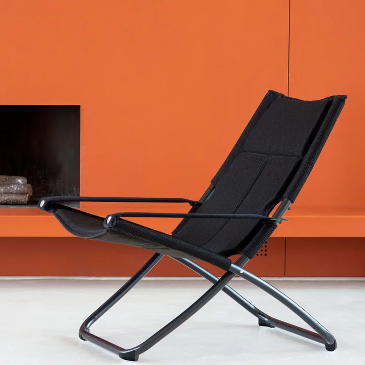 The Snooze deckchair Cozy from Emu in front of an orange wall
