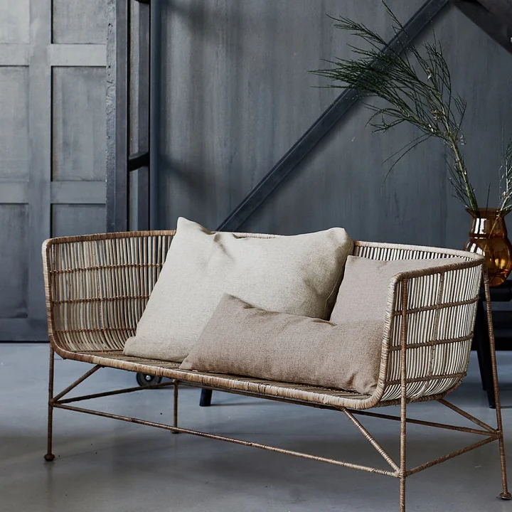 The Fine Outdoor cushions from House Doctor on a woven bench indoors