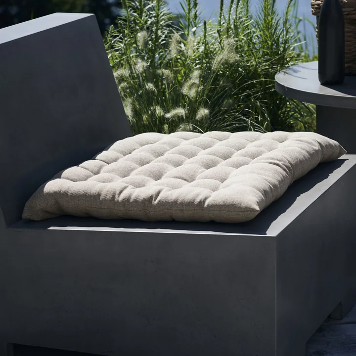 The Fine outdoor cushion from House Doctor on a concrete lounge chair.
