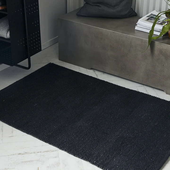 The black Hempi carpet runner from House Doctor in front of a concrete seating bench