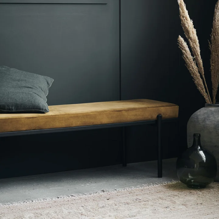 The Lao bench from House Doctor with cushions against a black wall