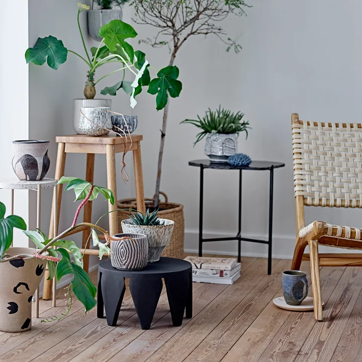 The Atena & Hena flowerpot from Bloomingville on a side table next to many plants