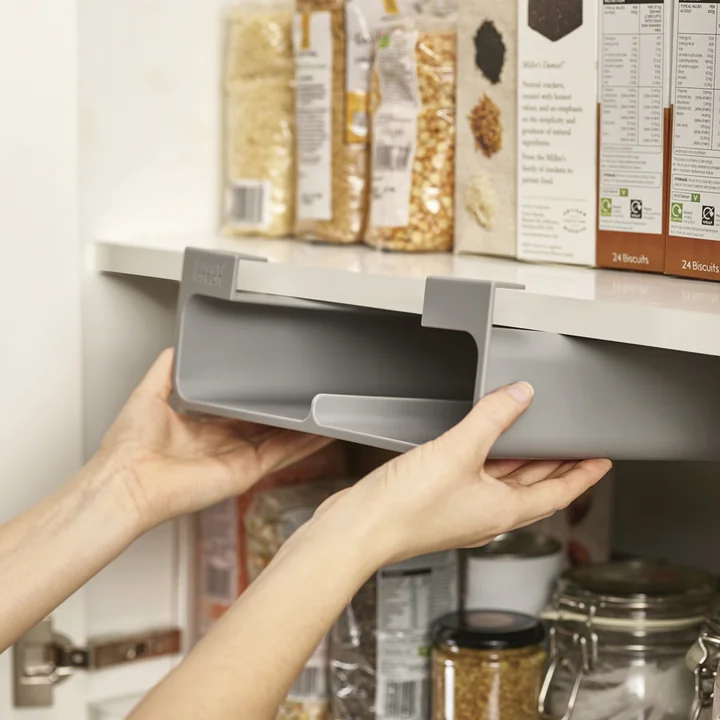 The CupboardStore organizer is held to the underside of the shelf by strong adhesive tape