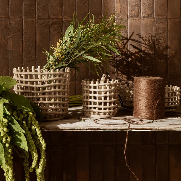 The ceramic baskets from Ferm Living with plants on a wooden bench