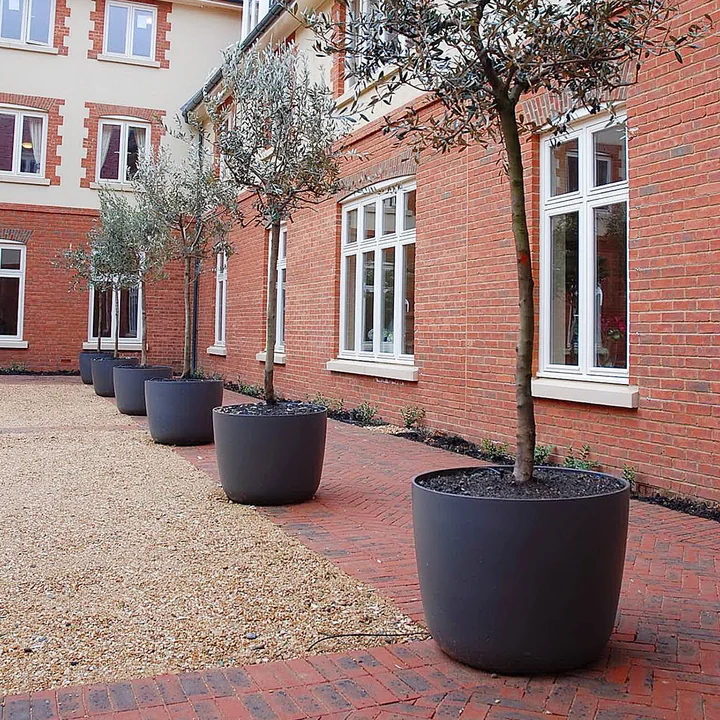 The Kyoto plant pot from Eternit in the courtyard of a large building.