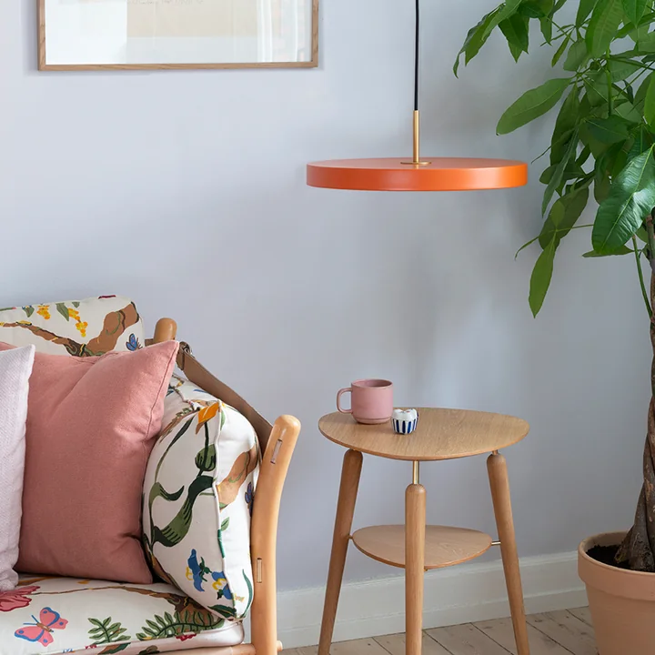 The orange Asteria Pendant light from Umage above the side table
