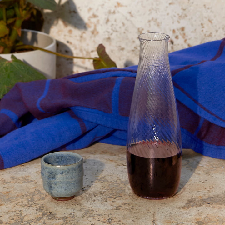 The Collect carafe and the Untitled bedspread from & Tradition on a stone bench