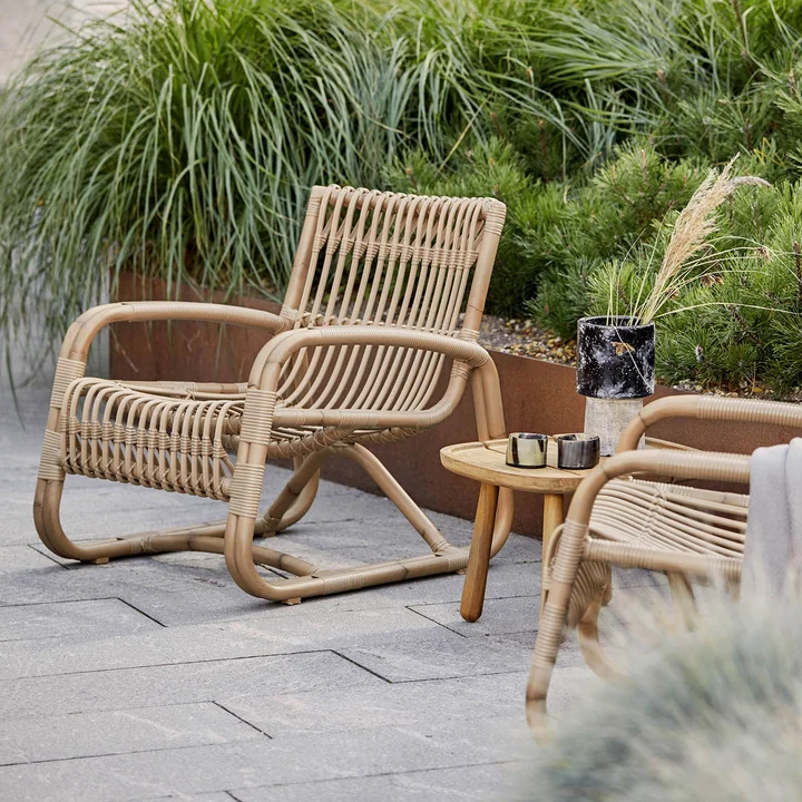 The Curve lounge chair Outdoor from Cane-line on the green planted terrace