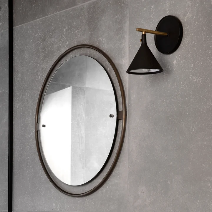Nimbus mirror from Audo in the finish burnished brass and Cast Sconce wall lamp with dimmer in the color black