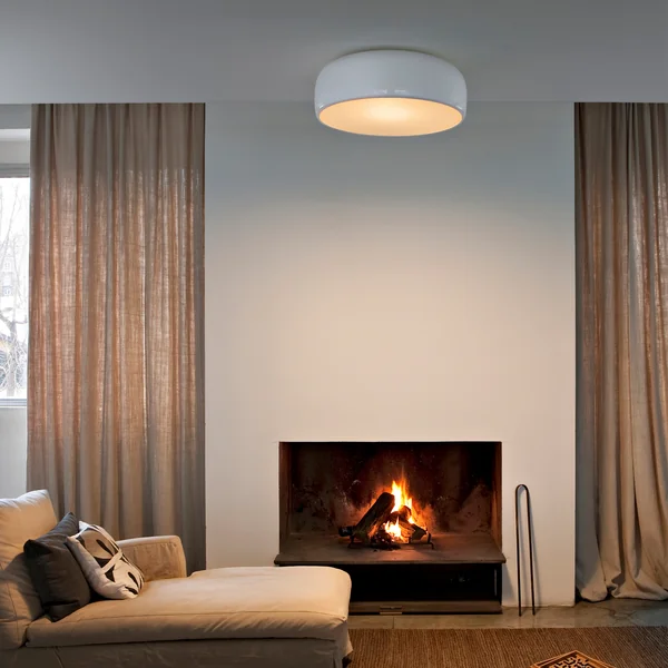 The Smithfield Pro ceiling lamp from Flos in the living room above a beige couch with fireplace